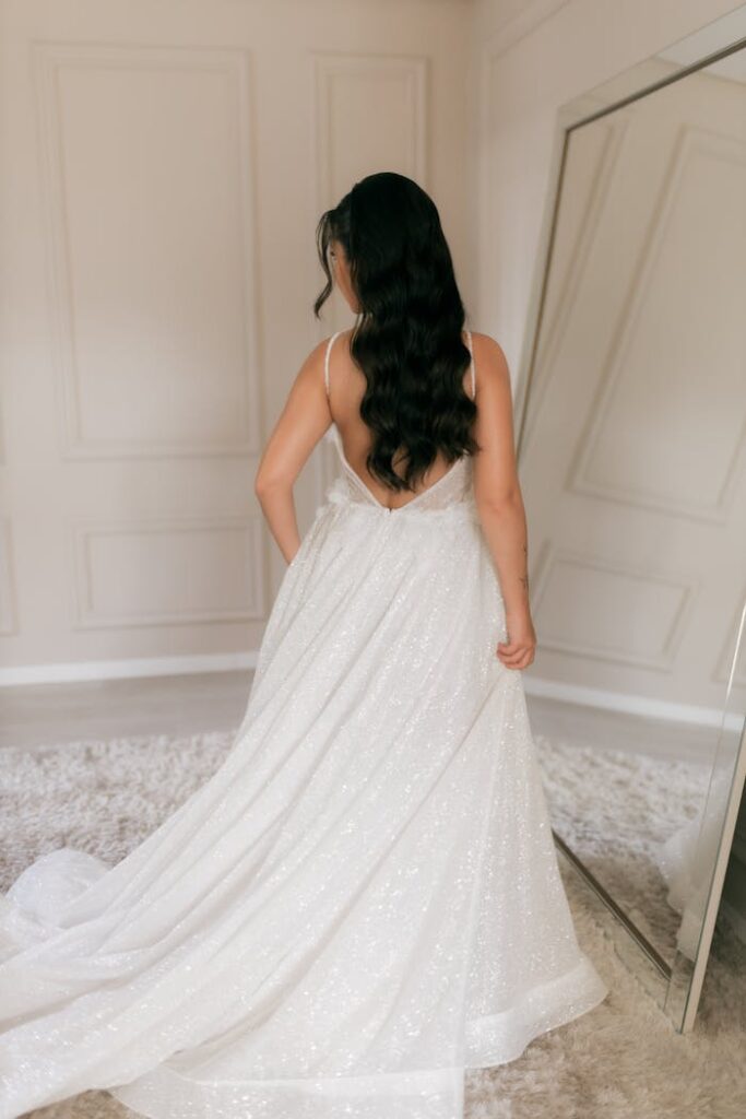 Bride showcasing a stunning sparkling wedding gown indoors, ideal for elegant weddings.