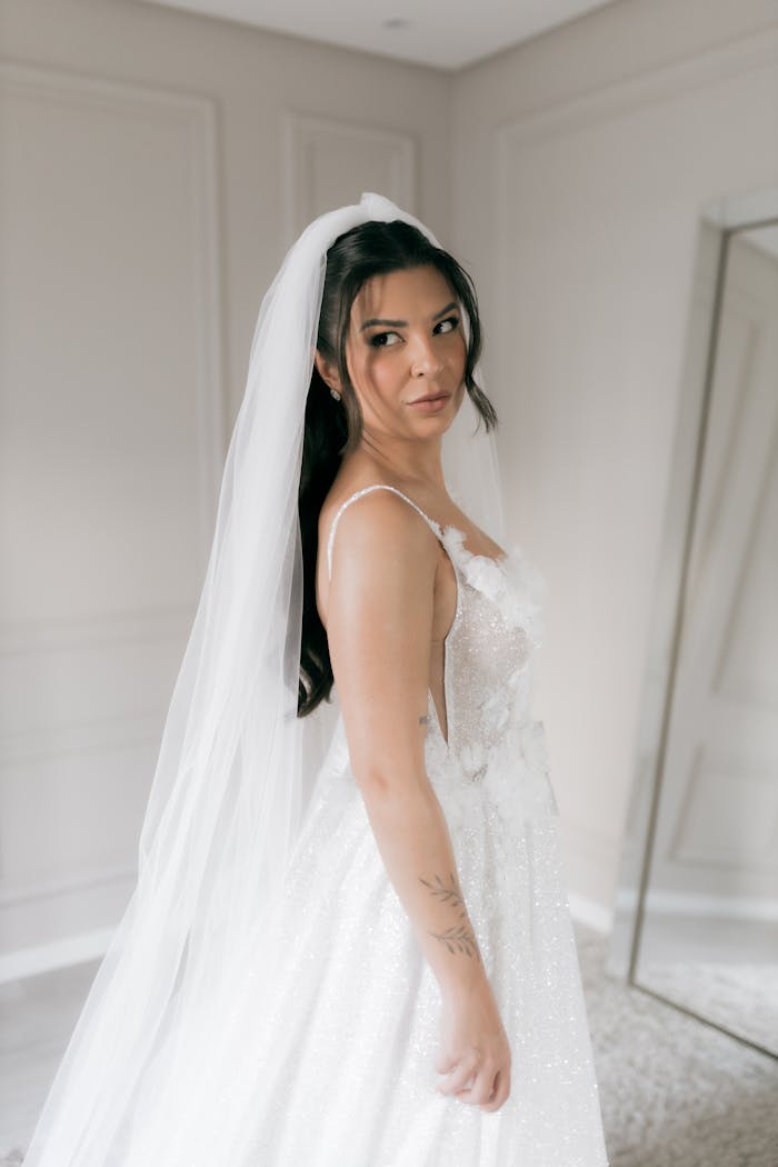 Portrait of a bride in a sparkling white gown with a veil in an elegant indoor setting.